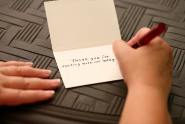 A hand writing the words Thank You For Meeting With Me on a s